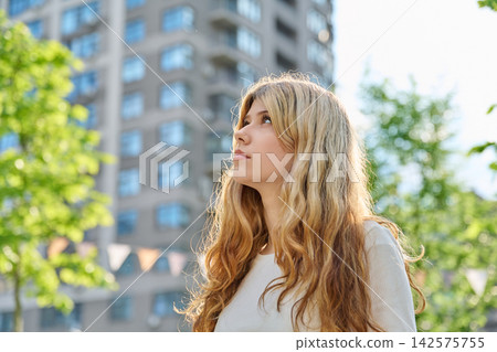 Pretty blonde teenage girl looking away in city Pretty blonde teenage girl looking away in city 142575755
