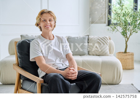 Smiling teenager student sitting in armchair indoor 142575758