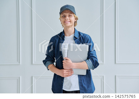Smiling teenager student holding laptop and notebook 142575765