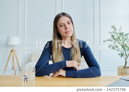 Webcam portrait female university student, sitting at the table with textbooks Webcam portrait female university student, sitting at the table with textbooks 142575786