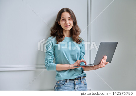 Young teen student girl with laptop looking at camera Young teen student girl with laptop looking at camera 142575790