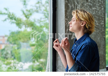 Peaceful young man meditating with eyes closed indoor Peaceful young man meditating with eyes closed indoor 142575793