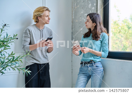 Teen friends talking to each other holding cellphones Teen friends talking to each other holding cellphones 142575807