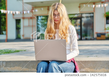 Teenage student working on laptop on school campus Teenage student working on laptop on school campus 142575816
