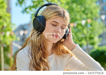 Teenage student listening to audio on campus laptop 142575818