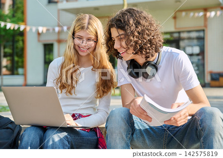 Happy teenage students studying with laptop on campus Happy teenage students studying with laptop on campus 142575819
