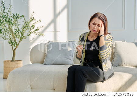 Mature sad woman experiencing stress, mental and physical pain, at home Mature sad woman experiencing stress, mental and physical pain, at home 142575885