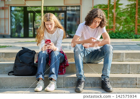 Teenage students using smartphones on school campus Teenage students using smartphones on school campus 142575934