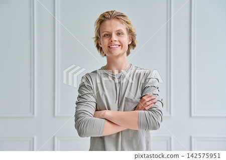 Confident teenage boy with crossed arms looking at camera against white background Confident teenage boy with crossed arms looking at camera against white background 142575951