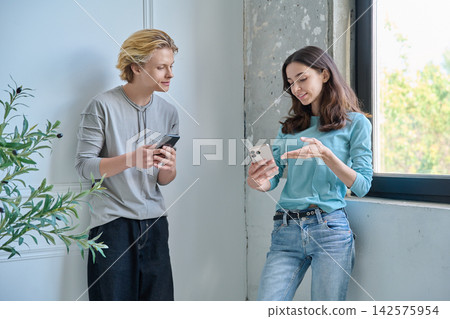 Teen friends talking to each other holding cellphones 142575954