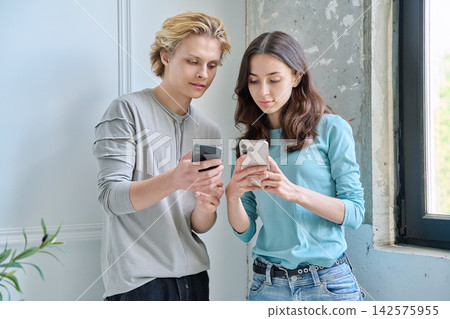 Teen friends looking together at smartphone screen Teen friends looking together at smartphone screen 142575955