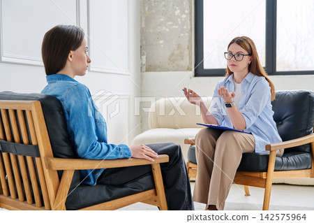 Young woman during consultation with female life coach or psychologist in modern office 142575964