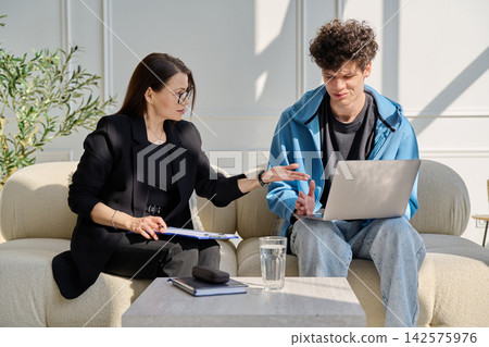 Professional female mentor therapist discussing content on laptop with teenage boy Professional female mentor therapist discussing content on laptop with teenage boy 142575976