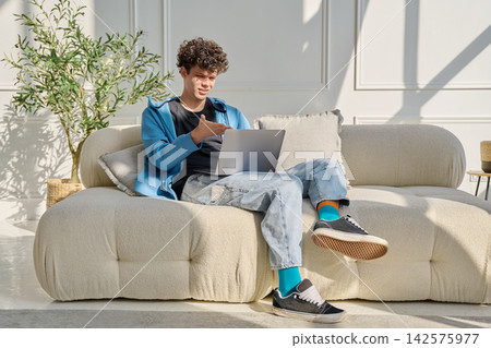 Young man using laptop for video call, online chat conference sitting at home Young man using laptop for video call, online chat conference sitting at home 142575977