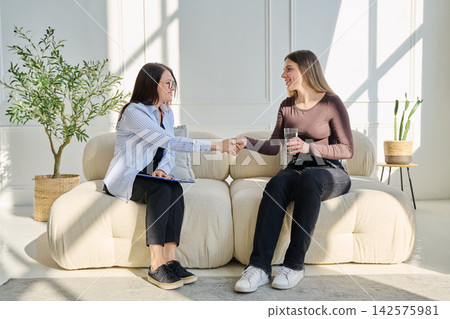Professional female psychologist, counselor listening to young woman client during therapy session Professional female psychologist, counselor listening to young woman client during therapy session 142575981