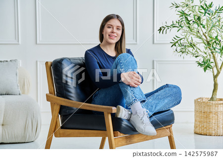 Portrait of relaxed beautiful young woman sitting at home on chair Portrait of relaxed beautiful young woman sitting at home on chair 142575987