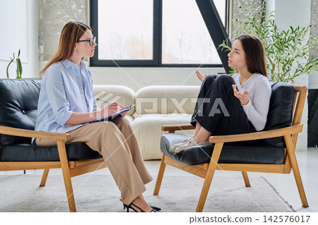 Professional therapist listens to a young woman during a session Professional therapist listens to a young woman during a session 142576017