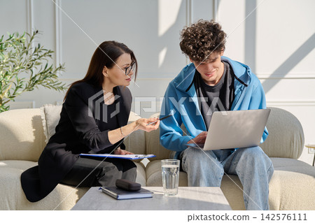 Professional female mentor therapist discussing content on laptop with teenage boy Professional female mentor therapist discussing content on laptop with teenage boy 142576111