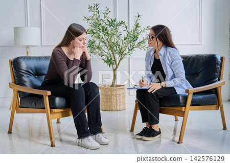Sad upset young woman patient in therapy session in psychologist office Sad upset young woman patient in therapy session in psychologist office 142576129