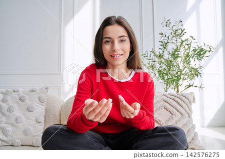 Young woman talking and gesturing during a video call, webcam view Young woman talking and gesturing during a video call, webcam view 142576275