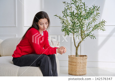 Sad unhappy stressed young woman sitting at home on sofa Sad unhappy stressed young woman sitting at home on sofa 142576347