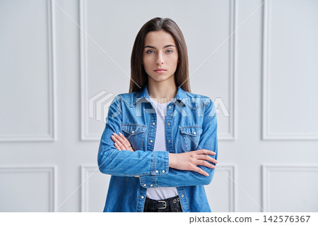 Happy confident young woman in denim shirt with arms crossed against white background Happy confident young woman in denim shirt with arms crossed against white background 142576367