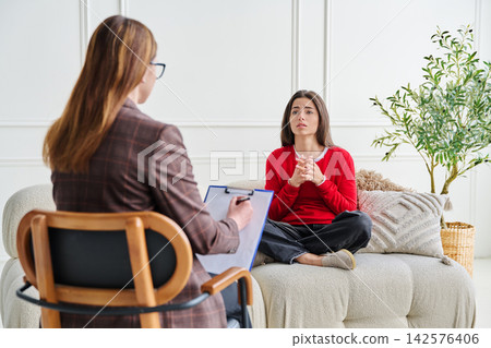 Sad teenage female patient in therapy session in psychologist office Sad teenage female patient in therapy session in psychologist office 142576406