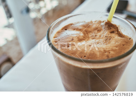 Close-up of a refreshing iced coffee frappe in a tall glass with a straw Close-up of a refreshing iced coffee frappe in a tall glass with a straw 142576819
