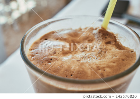 Close-up view of iced frappe coffee with thick creamy foam and yellow straw Close-up view of iced frappe coffee with thick creamy foam and yellow straw 142576820