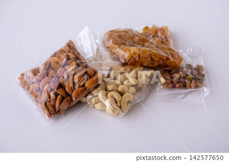 Assorted dry fruits packed in transparent plastic pouches placed on white background. Raw almonds, cashews, raisins, and pistachios packaged for healthy snacks. Assorted dry fruits packed in transparent plastic pouches placed on white background. Raw almonds, cashews, raisins, and pistachios packaged for healthy snacks. 142577650