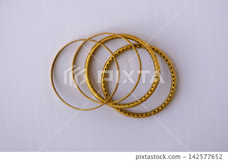 Four beautifully designed golden bangles displayed on clean white background. Luxury women jewelry bracelet set crafted for festive celebration and weddings. Top view. Four beautifully designed golden bangles displayed on clean white background. Luxury women jewelry bracelet set crafted for festive celebration and weddings. Top view. 142577652