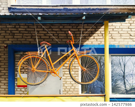Vintage yellow bicycle hanging in front of store entrance, side view Vintage yellow bicycle hanging in front of store entrance, side view 142577986