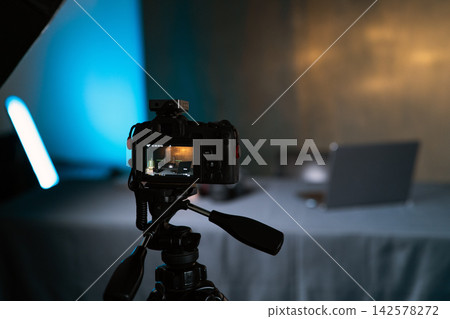 Professional DSLR camera on a tripod setup in a dark studio with blue led light shooting content Professional DSLR camera on a tripod setup in a dark studio with blue led light shooting content 142578272
