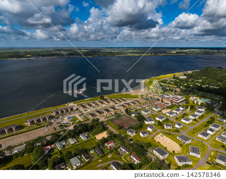 High angle wide horizontal aerial drone photograph of lakeside holiday park resort, solar chalets, sports court, marina jetty, and Lake Veere in Kamperland, Zeeland, Netherlands on sunny summer day High angle wide horizontal aerial drone photograph of lakeside holiday park resort, solar chalets, sports court, marina jetty, and Lake Veere in Kamperland, Zeeland, Netherlands on sunny summer day 142578346