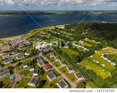 High angle wide horizontal aerial drone photograph of lakeside holiday resort, solar chalets, outdoor pool complex, campsite, and Lake Veere in Kamperland, Zeeland, Netherlands on sunny summer day High angle wide horizontal aerial drone photograph of lakeside holiday resort, solar chalets, outdoor pool complex, campsite, and Lake Veere in Kamperland, Zeeland, Netherlands on sunny summer day 142578349