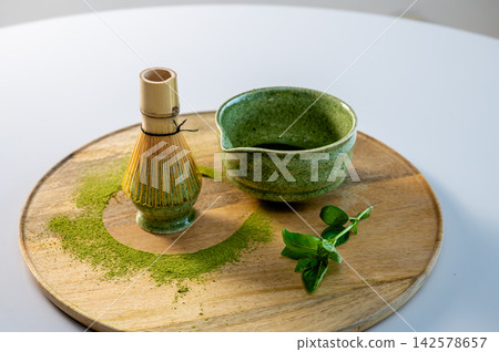 Matcha Tea Setup with Herbs and Garden Atmosphere. Matcha tea ceremony setup with fresh herbs and mint leaves in garden-like atmosphere. Bowl with whisk and organic accessories on wooden tray Matcha Tea Setup with Herbs and Garden Atmosphere. Matcha tea ceremony setup with fresh herbs and mint leaves in garden-like atmosphere. Bowl with whisk and organic accessories on wooden tray 142578657