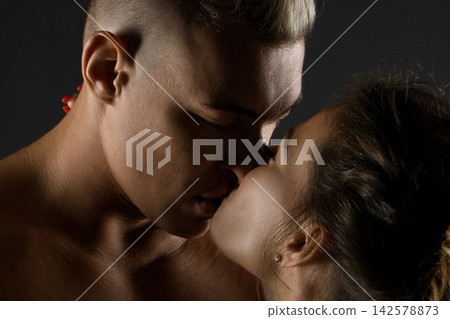 Young attractive couple sharing a tender kiss in a close up studio shot Young attractive couple sharing a tender kiss in a close up studio shot 142578873