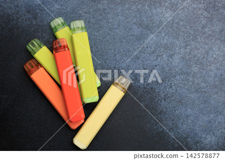 Different electronic cigarettes placed together on a flat surface showing various colors and designs a modern alternative to regular cigarettes Different electronic cigarettes placed together on a flat surface showing various colors and designs a modern alternative to regular cigarettes 142578877