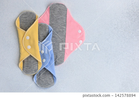 Reusable period cloth menstrual pads in different colors on gray backdrop for sustainable hygiene solutions Reusable period cloth menstrual pads in different colors on gray backdrop for sustainable hygiene solutions 142578894