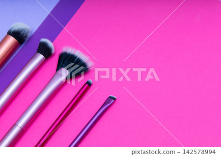Different types of makeup brushes arranged on a bright colored background with shades of pink and purple Different types of makeup brushes arranged on a bright colored background with shades of pink and purple 142578994