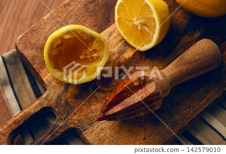 lemons and a wooden manual citrus juicer, on a chopping board, close-up, no people, 142579010