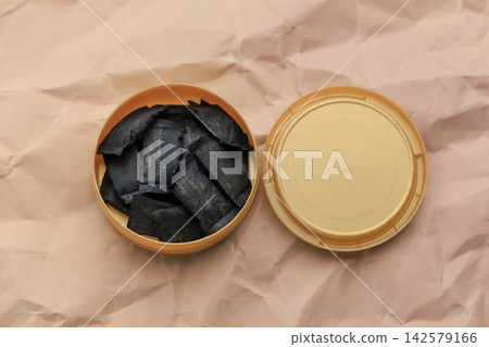 Snus pouches are arranged inside a round tin on a textured surface during a casual setting Snus pouches are arranged inside a round tin on a textured surface during a casual setting 142579166