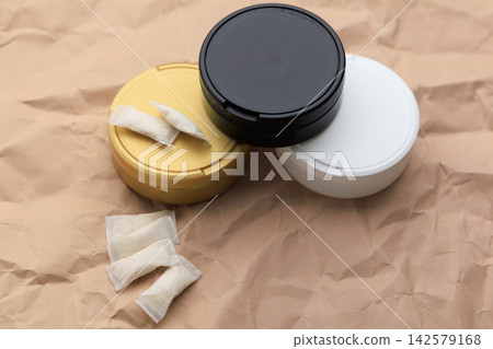 Snus pouches and containers placed on brown paper surface in casual setting Snus pouches and containers placed on brown paper surface in casual setting 142579168