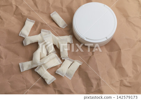 Snus pouches and container placed on crumpled paper with a simple display of nicotine products Snus pouches and container placed on crumpled paper with a simple display of nicotine products 142579173