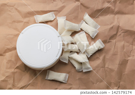 Various snus pouches and a container are seen on crumpled brown paper Various snus pouches and a container are seen on crumpled brown paper 142579174