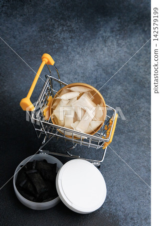 Snus pouches in shopping cart with nicotine pads nearby on a dark surface Snus pouches in shopping cart with nicotine pads nearby on a dark surface 142579199