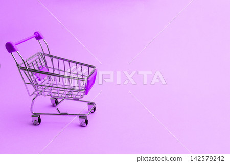 Shopping cart on a purple background with a simple design and bright colors in a retail setting for modern merchandise display Shopping cart on a purple background with a simple design and bright colors in a retail setting for modern merchandise display 142579242