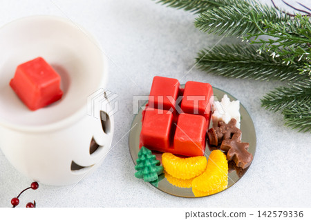 Warm glow from aroma lamp with Christmas wax melts on a table with decorative items 142579336