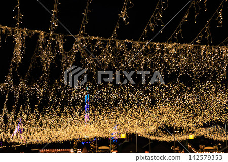 String lights hang from above at a Christmas festive event at night creating a bright atmosphere for people below String lights hang from above at a Christmas festive event at night creating a bright atmosphere for people below 142579353