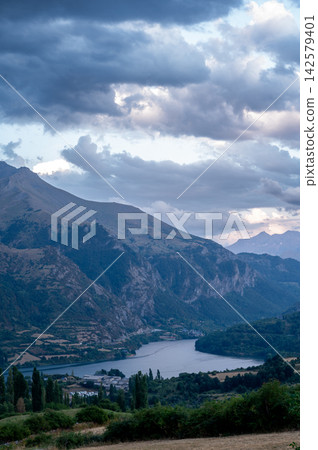 Reservoir and Pyrenees Under Evening Clouds. A vertical view over the Lanuza reservoir and the mountains of the Spanish Pyrenees under dramatic evening clouds near Formigal, Spain, a moody and serene Reservoir and Pyrenees Under Evening Clouds. A vertical view over the Lanuza reservoir and the mountains of the Spanish Pyrenees under dramatic evening clouds near Formigal, Spain, a moody and serene 142579401